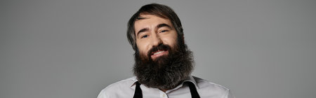 A man with a long beard smiles warmly for the camera.