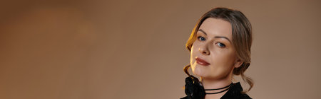 A woman in a sophisticated black dress looks directly at the camera, her gaze captivating.の写真素材