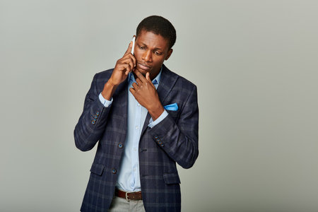 Handsome African American man in suit having phone callの写真素材