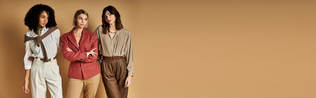 Multicultural women in stylish attire stand together, showcasing diversity and friendship on a beige...