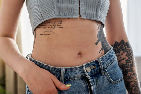 A young woman with multiple tattoos relaxes at home in a modern apartment, enjoying a cozy weekend.の写真素材