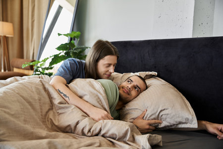 A young gay couple cuddles in bed, sharing a tender moment of intimacy.