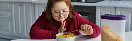 A little girl with Down syndrome enjoys a meal at home.