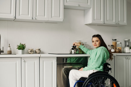 A young brunette woman in a wheelchair is preparing dinner in her kitchen. She is wearing a green...