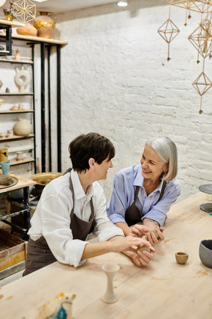 Two women working with clay in a pottery studio, with a relaxed and loving atmosphere.