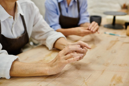 A close-up of a lesbian couples hands while crafting in a cozy pottery studio.の写真素材