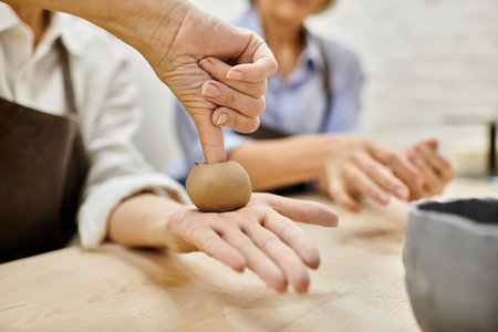 A close-up of a womans hand shaping clay, showcasing the intimate artistry of pottery.の写真素材