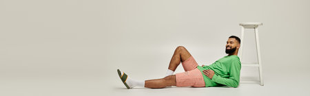 Handsome African American man sitting on vibrant backdrop.