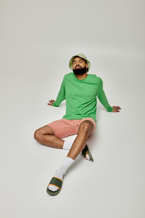 Handsome African American man in green shirt and pink shorts posing outdoors.