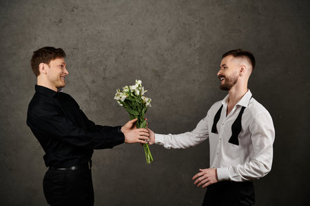 Two men in elegant suits, one presenting a bouquet of white flowers to the other.の写真素材