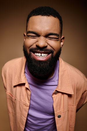 Fashionable African American man with beard wearing a pink shirt against vibrant background.