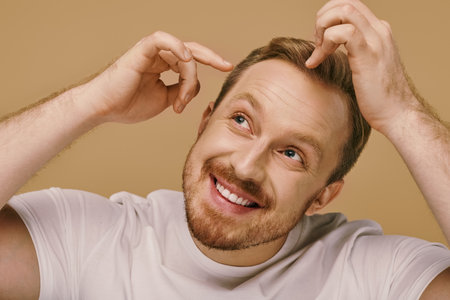A man with a goatee smiles, holding his hair stylishly.