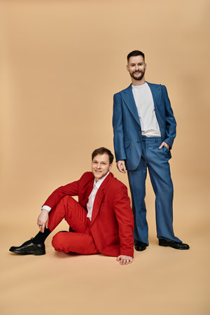 Two men in suits pose for a photograph, one standing and one sitting.の写真素材