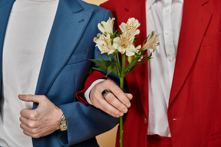A gay couple in elegant suits, one presenting a bouquet of white flowers to the other.の写真素材