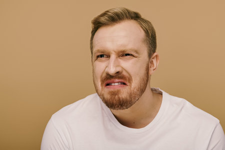 A stylish man with a beard in a white shirt striking a pose.