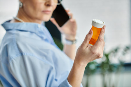 Middle-aged businesswoman in a blue shirt holding orange bottle with medicationの写真素材