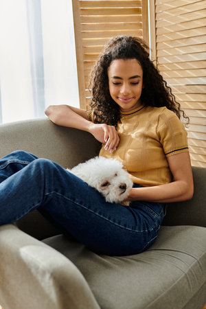 A woman relaxes on the couch while holding her small white dog.の写真素材