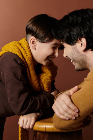 A father and his son look into each others eyes, both smiling warmly.