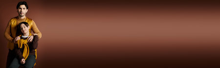 A father and son stand close together against a brown backgroundの写真素材