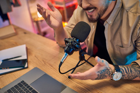 An Asian man records a podcast in a studio, speaking into a microphone with enthusiasm.の写真素材