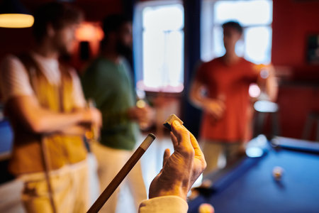 A group of friends casually play billiards in a dimly lit room.