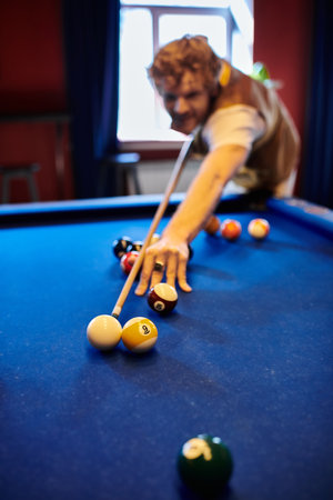 A man plays billiards, focused on lining up a shot.の写真素材