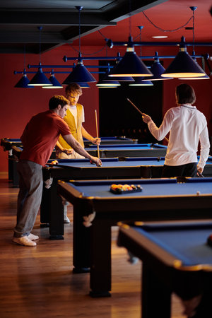 Friends play billiards in a dimly lit room, enjoying a fun evening out.