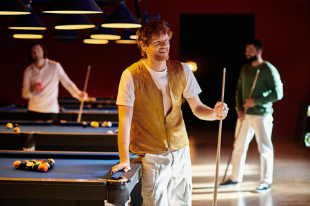 Friends enjoy a casual game of billiards in a dimly lit pool hall.の写真素材