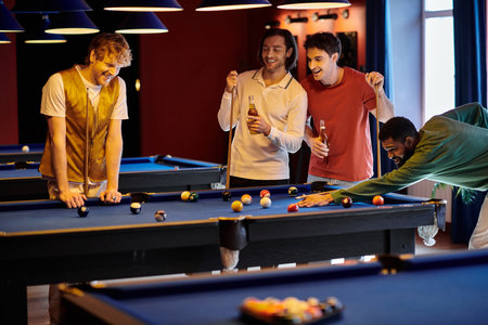 Friends enjoy a casual game of billiards in a dimly lit room.の写真素材