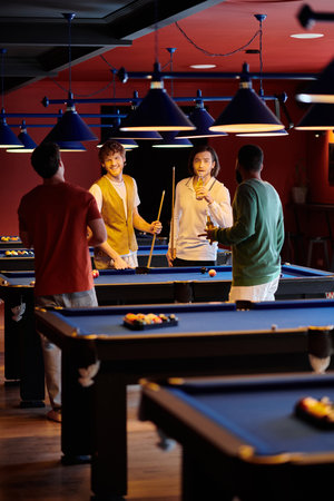 Friends casually dressed play billiards in a dimly lit lounge with blue overhead lights.