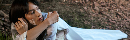 A woman in elegant attire poses near a swamp.の写真素材