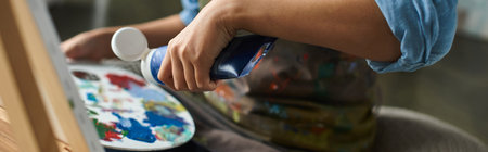 Close-up of artists hand squeezing paint onto a palette.
