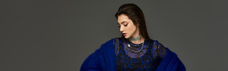 A young woman in a blue outfit, looking downwards in a moment of thought.