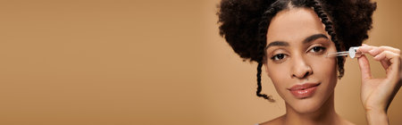 A young African American woman applies serum to her face while looking at the camera.の写真素材