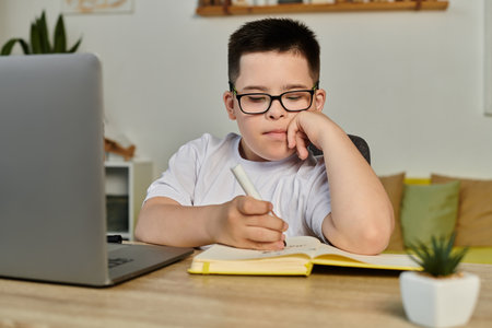 A young boy with Down syndrome concentrates on his schoolwork at home.の写真素材