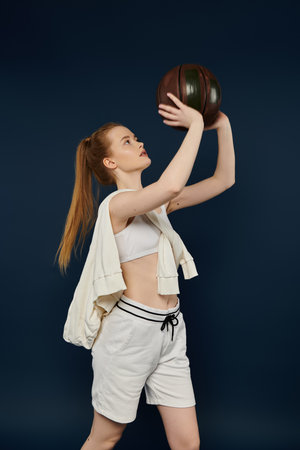 Young woman gracefully holds basketball against vibrant backdrop.の写真素材