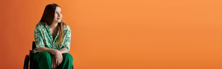 A young woman in a vibrant green and white shirt sits in a wheelchair against a bright orange...