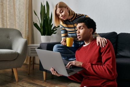 A happy multicultural couple spends quality time together in a modern apartment, looking at a laptop and enjoying each others company.の写真素材