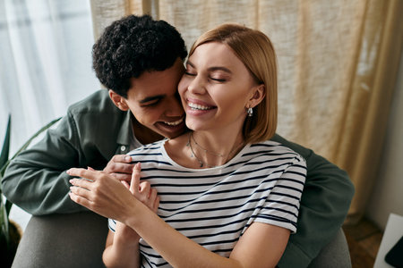 A young, multicultural couple enjoys a moment of intimacy and laughter in their modern apartment.の写真素材