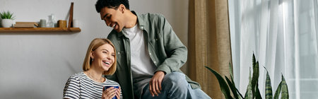 A young multicultural couple shares a laugh while spending time in their modern apartment.
