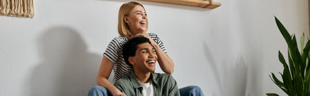 A young, multicultural couple enjoys a playful moment in their modern apartment.