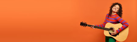 A young woman with curly hair poses with a guitar, smiling brightly against a bright orange background.の写真素材