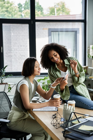 Lesbian couple collaborate at office desk, sharing moment.の写真素材