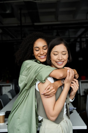 Two women, a lesbian couple, are seen hugging each other affectionately in an office setting.
