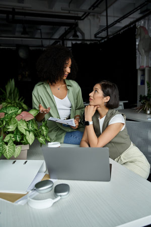 Two women working together on a project in an office setting.
