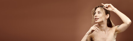 A young woman with vitiligo poses with her shoulders bare against a beige backdrop.