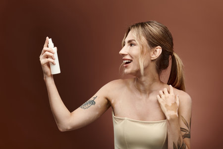 A young woman with vitiligo smiles as she applies skincare to her arm.の写真素材