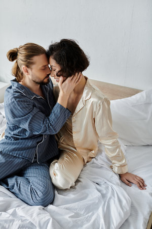 Couple in pajamas sharing a loving moment, foreheads touching in deep connection.の写真素材