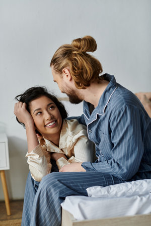 A loving couple is relaxing on their bed in pajamas.の写真素材
