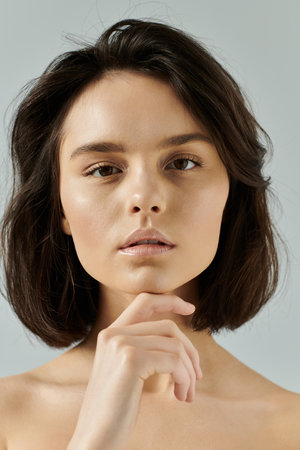 A woman with short, dark hair contemplates in front of a simple background.の写真素材